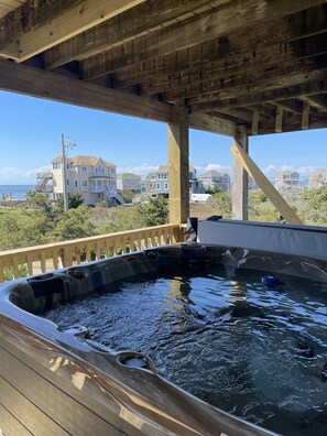 A hot tub under a wooden deck with a view of houses and the ocean. - Hole in the Wall- Sound Side with Hot Tub! (Avon)