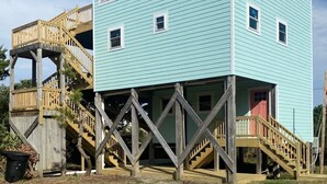 Ein zweistöckiges Haus mit einer Holzterrasse und einer Treppe, die zu einer Veranda führt.