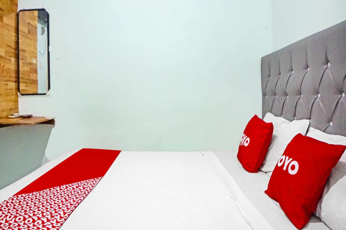 Hotellihuone, jossa on sänky, sängynpääty ja puinen hylly.