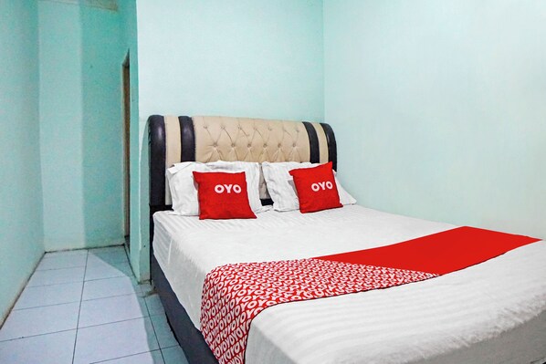 A neatly made bed with a white and red patterned bedspread and two pillows with the word "OYO" on them. - OYO 91303 Puri Dennis (Medan)