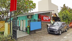 A building with a blue door, a red sign, and a parked car.