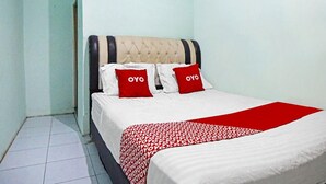 A neatly made bed with a red and white patterned bedspread and two red pillows with the word "OYO" on them.