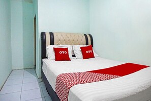 A neatly made bed with a red and white patterned bedspread and two red pillows with the word "OYO" on them. - OYO 91303 Puri Dennis (Medan)