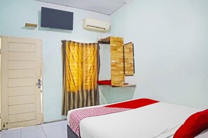 A room with a bed, a door, an air conditioner, a mirror, and a curtain. - OYO 91303 Puri Dennis (Medan)
