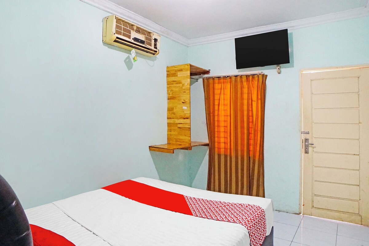 Quarto com cama, ar condicionado, televisão e porta.