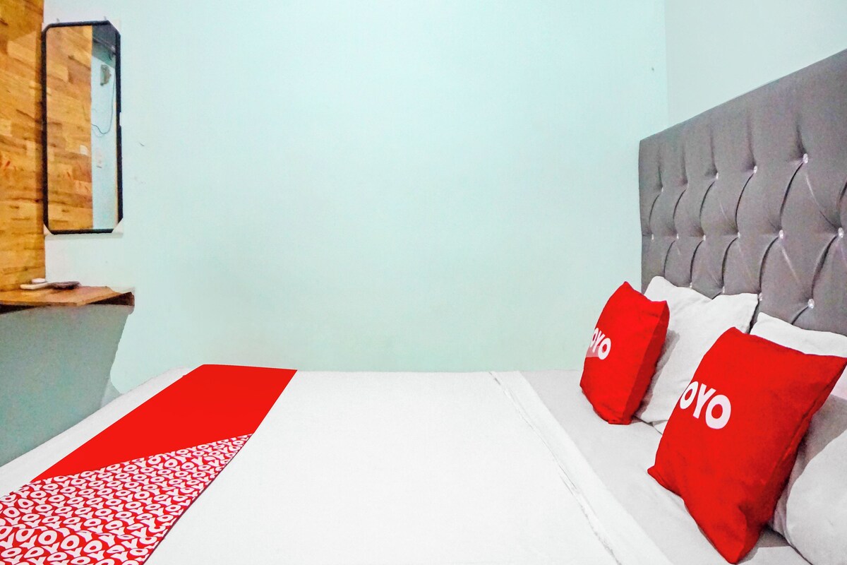 Ein Hotelzimmer mit Bett, Kopfteil und einem Wandbild.
