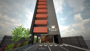 A modern hotel with a vertical design, featuring a mix of red and black panels, and a sign indicating it is the Henn na Hotel.