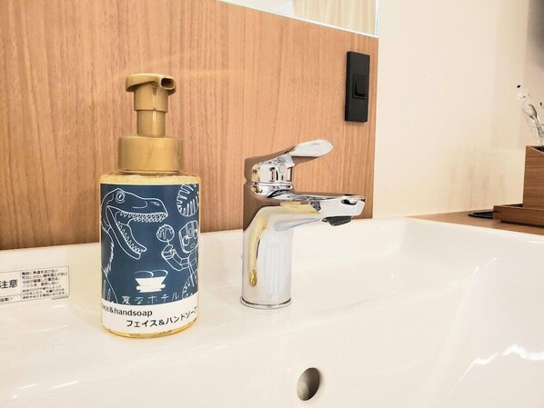 A bathroom with a white sink, a gold-colored soap dispenser, and a chrome faucet.