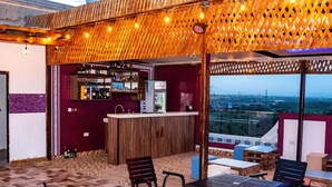 Een terras met een bar, houten meubels en uitzicht op de skyline.