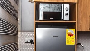 Een kleine keuken met een magnetron, een Hisense koelkast en een gasfornuis.