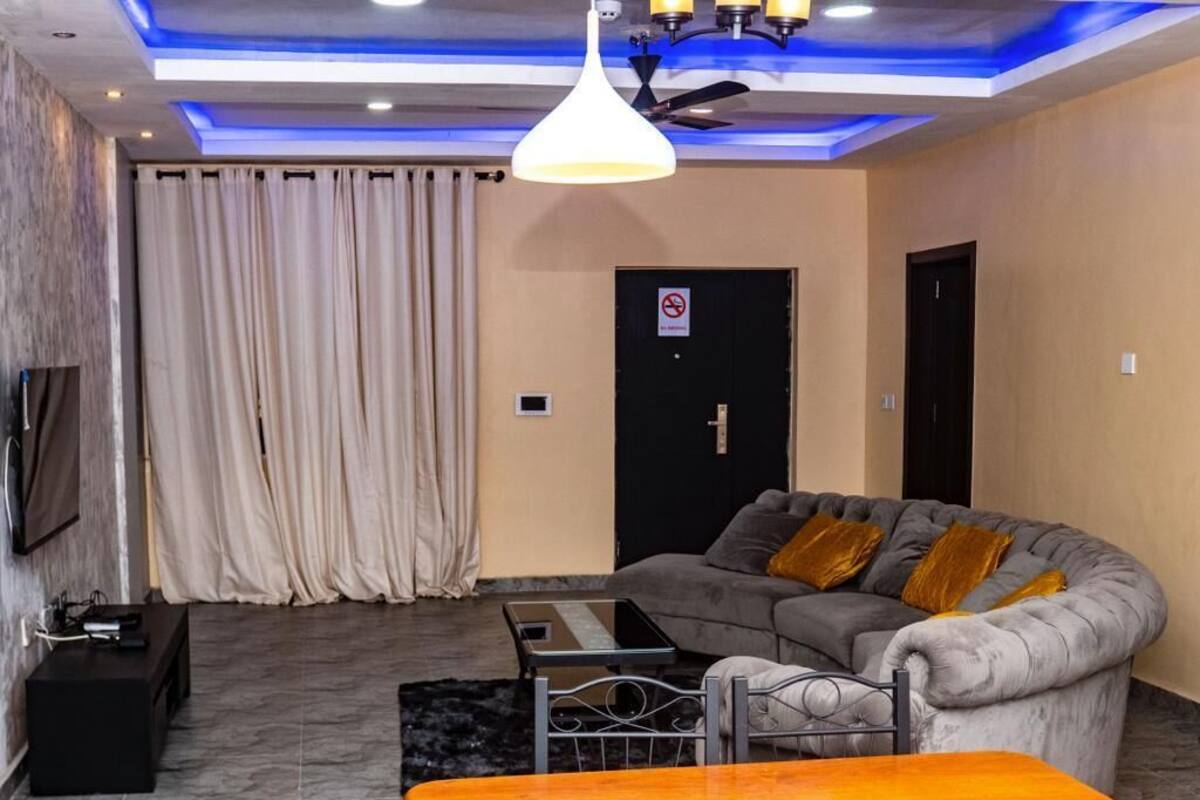A living room with a grey sofa, a wooden table, and a TV mounted on the wall.