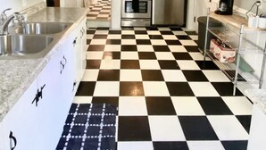 Une cuisine avec un carrelage à motifs, des appareils électroménagers en acier inoxydable et des meubles blancs.