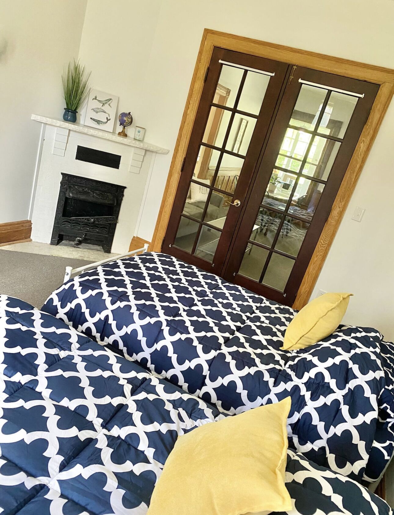 A bedroom with a large bed, a fireplace, and a door with glass panels.