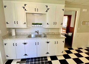 A kitchen with white cabinets, a sink, and a checkered floor.