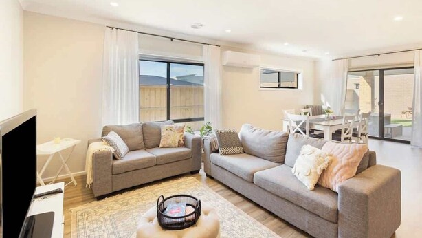 A living room with two sofas, a TV, and a dining area with a table and chairs. - Modern Beach House w/ BBQ & Family-Friendly Charm (Cowes)