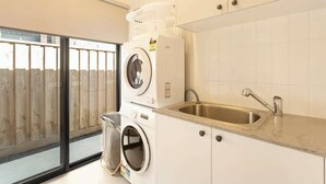 A laundry area with stacked washing machines and a sink. - Modern Beach House w/ BBQ & Family-Friendly Charm (Cowes)