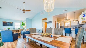 A spacious dining area with a wooden table, blue upholstered chairs, and a chandelier. - La Carolina del Mar - KDH MP 5.5, 250 Yds to Beach, Ocean View, Hot Tub, Flex Stays (Kill Devil Hills)
