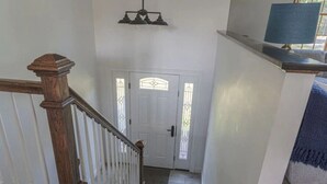 A staircase with a wooden handrail leading to a white door with decorative glass panels.