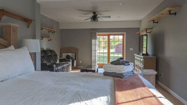 Un dormitorio con una cama grande, una silla, un televisor y una chimenea.