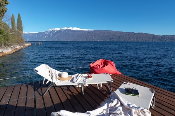 A wooden deck with a lounge chair, a small table, and a red bag.
