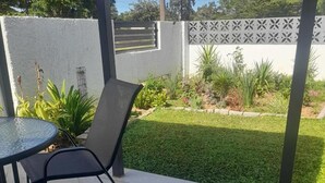 A patio area with a table and chairs, surrounded by a well-maintained lawn and a decorative fence. - Phakela Cottages (Jwaneng)