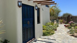A building with a blue door, stone pathway, and outdoor plants.