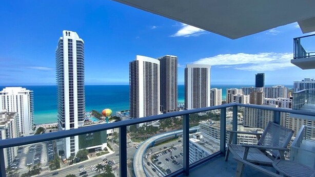 A balcony with a view of tall buildings and the ocean. - Suite Ocean View w/JACUZZI, POOL, GYM and MORE (Hollywood)