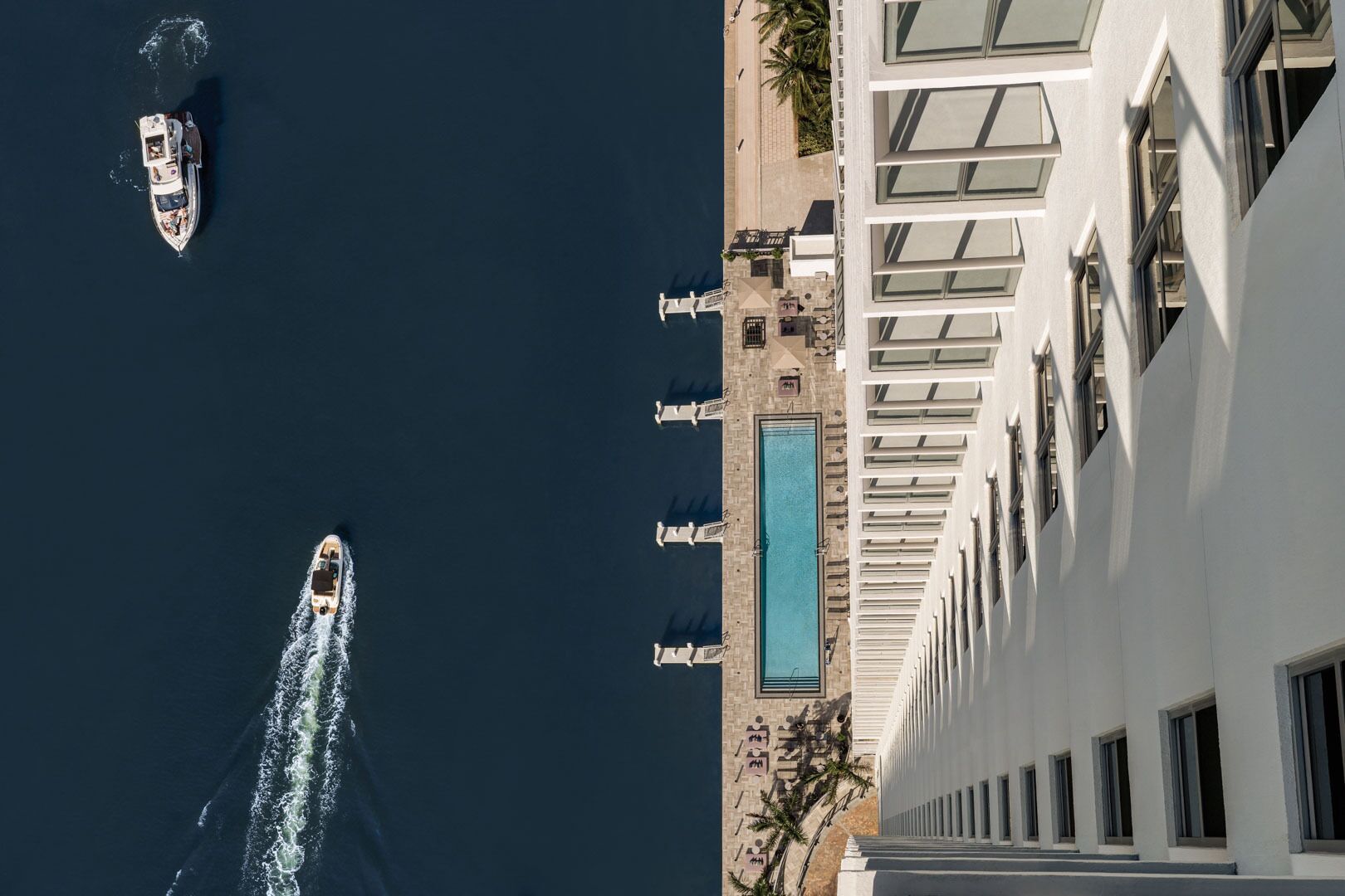 A high-rise hotel with a pool and multiple balconies overlooking the sea.