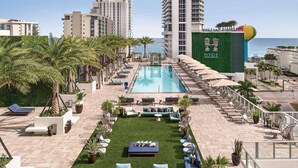 A rooftop pool area with lounge chairs, a small lawn, and a view of the sea. - Suite Ocean View w/JACUZZI, POOL, GYM and MORE (Hollywood)