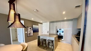 A modern kitchen with a central island, bar stools, and a dining area with a round table and chairs. - Suite Ocean View w/JACUZZI, POOL, GYM and MORE (Hollywood)