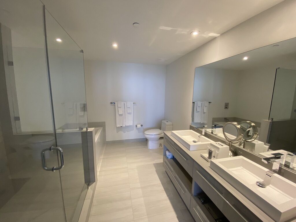 Un baño moderno con cabina de ducha de vidrio, un espejo grande y un tocador doble.