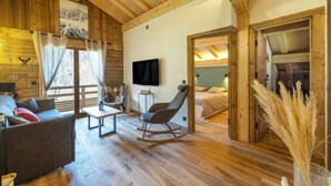 Ein Holzinnenraum mit einer Couch, einem Schaukelstuhl, einem Fernseher und einem Bett.