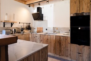 A modern kitchen with wooden cabinets, a marble countertop, and built-in appliances.