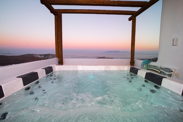 A hot tub with a view of the ocean during sunset.