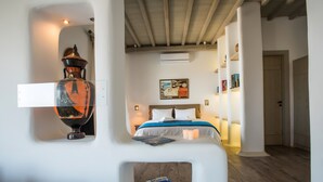 Une chambre à coucher avec un lit, un vase fixé au mur, un tableau et une petite table sur laquelle est posé un jeu de société.