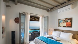 Une chambre avec un lit, une vue sur la mer, un coin repas et un appareil de climatisation.