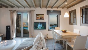 Quarto moderno com cama, mesa de jantar e televisão.