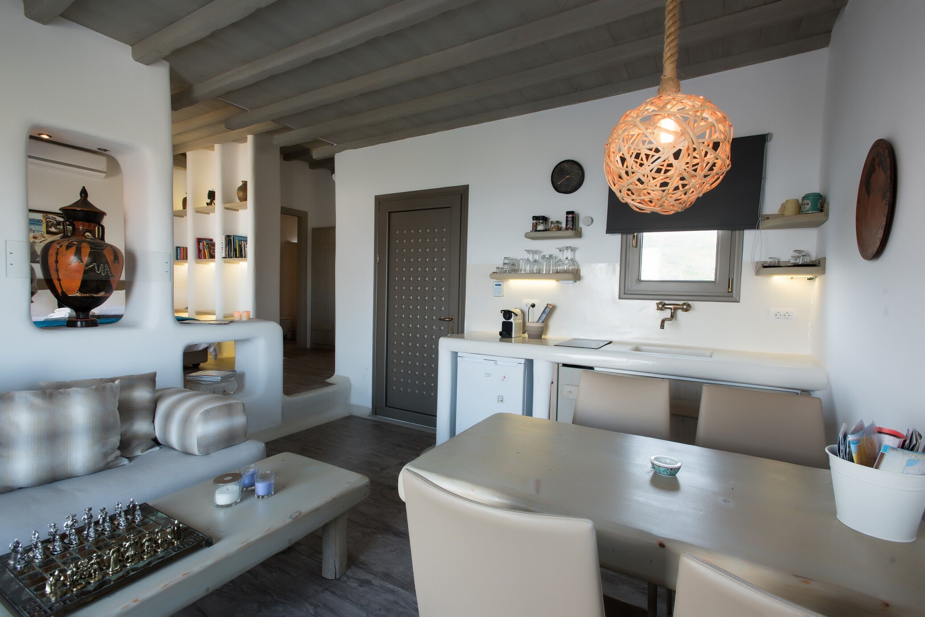 A modern living room with a sofa, a dining table, and a kitchen area with a refrigerator and sink.