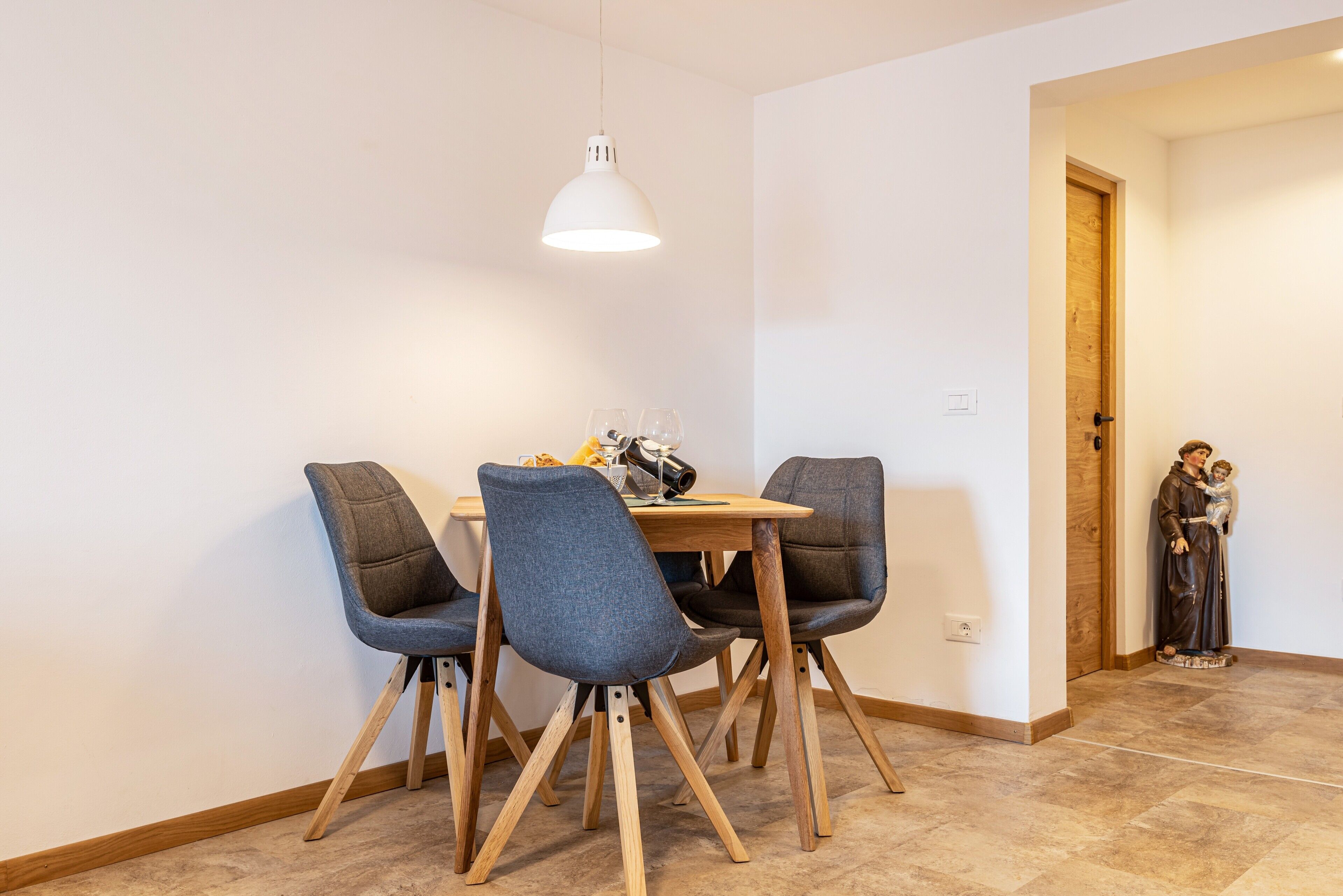 Een eethoek met een tafel, stoelen en een hanglamp.
