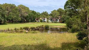 A golf course with a pond, surrounded by trees and buildings. - Villa 'Christine' with Shared Pool, Shared Garden, and Balcony (Moliets-et-Maa)