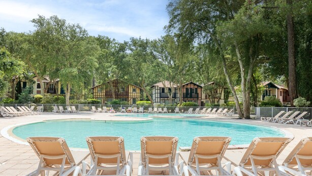 A swimming pool with lounge chairs, surrounded by trees and buildings. - Villa 'Christine' with Shared Pool, Shared Garden, and Balcony (Moliets-et-Maa)