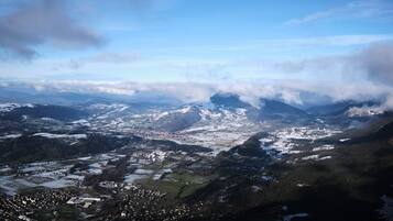 Un paysage montagneux avec une ville nichée dans une vallée, entourée de collines et de forêts couvertes de neige.
