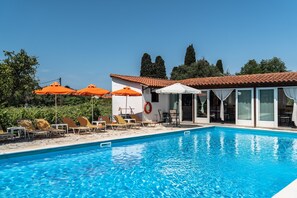 A swimming pool with sun loungers and umbrellas, a covered seating area, and a building with a tiled roof. - Apartment 'Marketos  Maisonette  4pax' with Mountain View, Wi-Fi and Air Conditioning (Kefalonia)