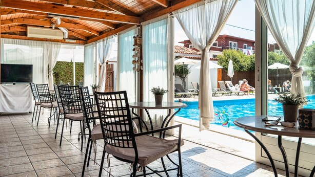 Un espacio al aire libre techado con piscina, sillas y mesas.