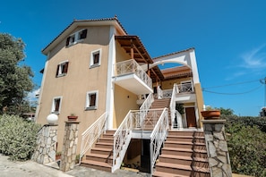 A multi-story building with a balcony, stone steps, and a door.