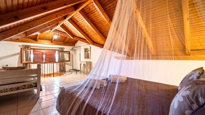 Un dormitorio con techo de madera, cama con dosel y vistas a un área de baño y cocina.