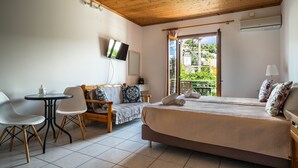 A bedroom with a bed, a TV, a table, and chairs. - Loft Apartment 'Marketos Studio  2' with Mountain View, Wi-Fi and Air Conditioning (Kefalonia)
