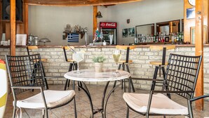 A bar area with a stone wall, wooden ceiling, and a Coca-Cola refrigerator. - Loft Apartment 'Marketos Studio  2' with Mountain View, Wi-Fi and Air Conditioning (Kefalonia)
