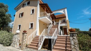 Un edificio a più piani con un balcone, gradini in pietra e una porta.
