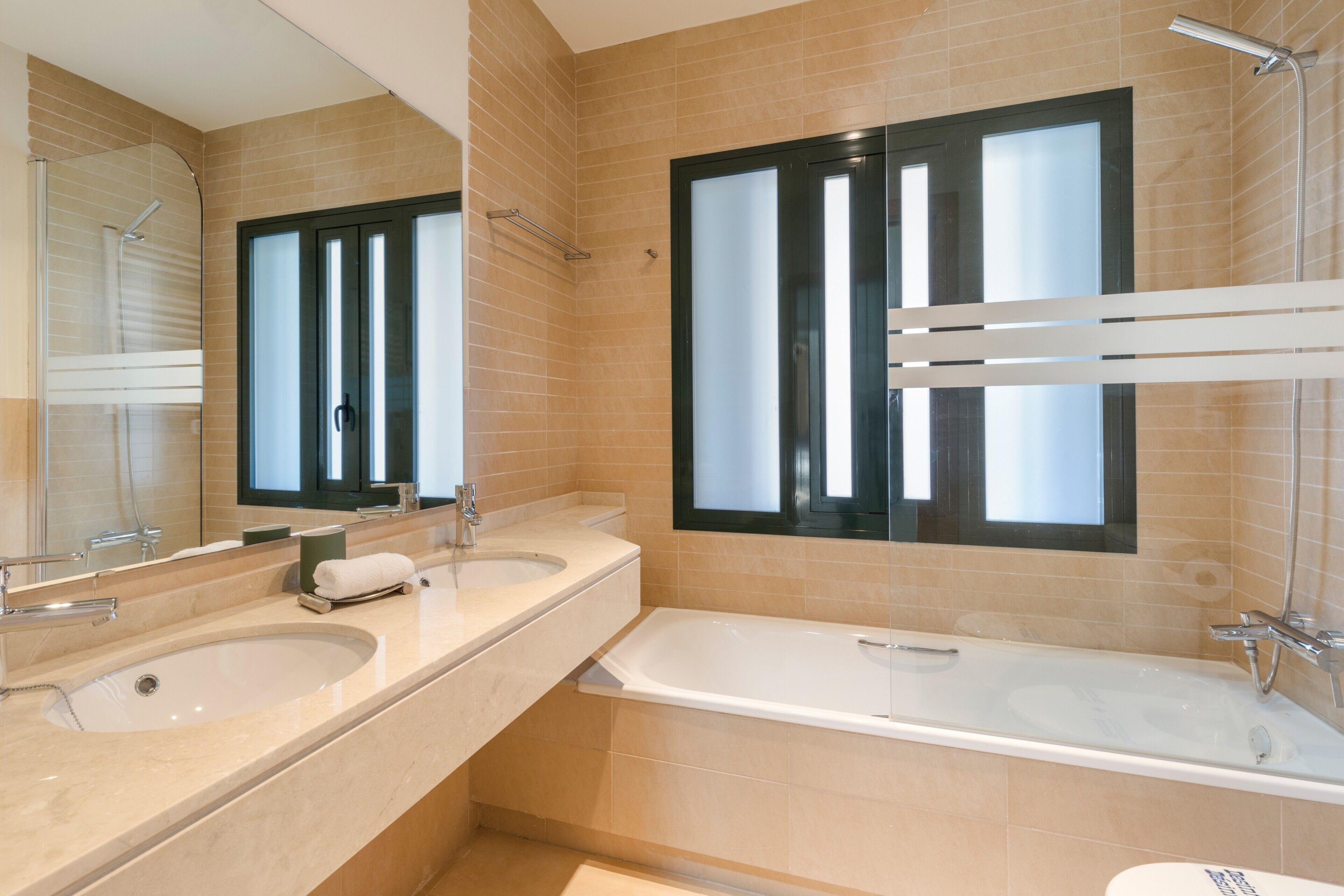 Un baño con dos lavabos, una bañera y una ducha.
